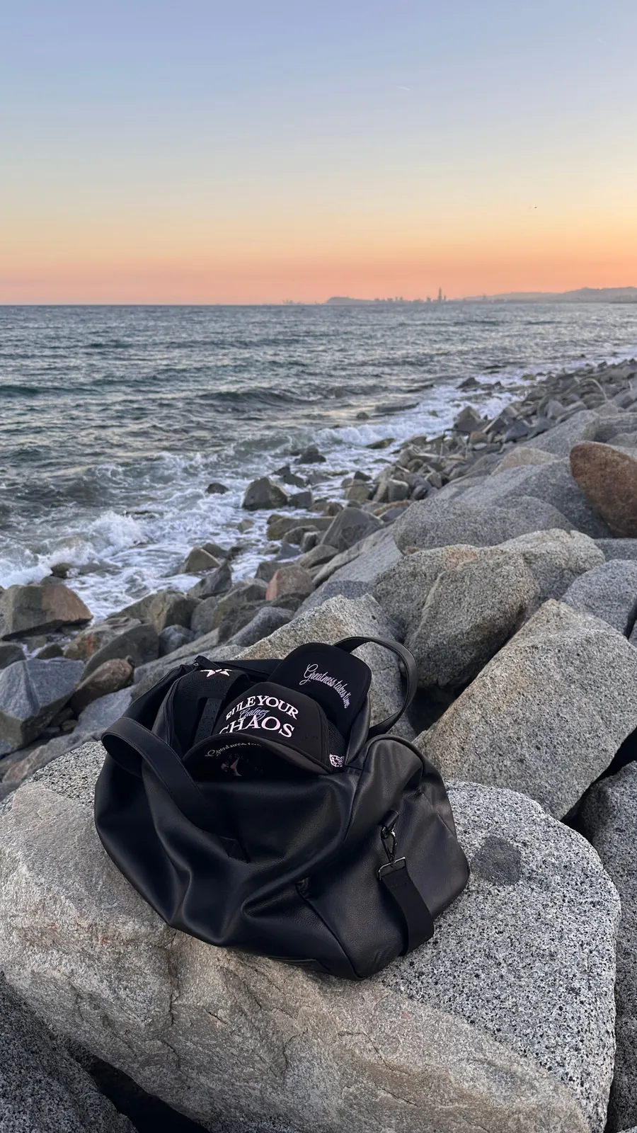 GALNEZ caps and bag on seaside rocks at sunset