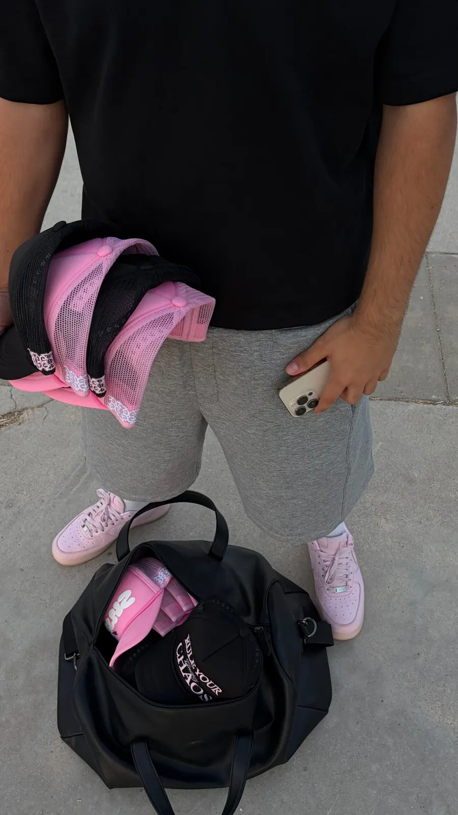 Holding pink GALNEZ caps next to a black duffle bag