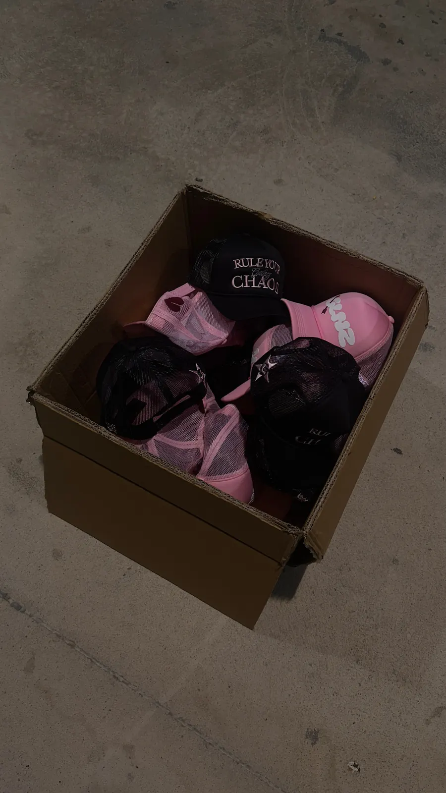 Box of pink and black GALNEZ caps on concrete floor